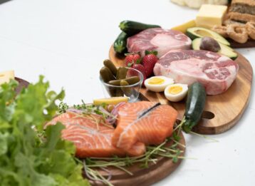 Rohes Fleisch auf einem Holzbrett mit verschiedenen Beilagen
