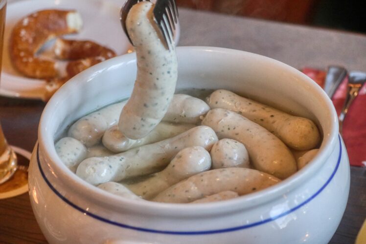 Was ist Weißwurst, woher kommt sie und wie isst man sie richtig? Alles zu Inhalt, Weißwurstfrühstück, Zuzeln und schlesischer Weißwurst.